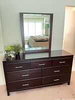 Front view of espresso dresser with attached mirror showing seven drawers and metal pulls