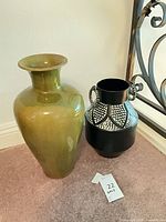 Green ceramic vase and black patterned metal vase side by side