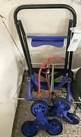 Stair-climbing hand truck folded with blue tri-wheel hubs and bungee cords