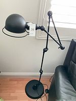 Full view of black metal adjustable floor lamp beside sofa