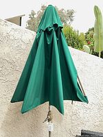 Closed green patio umbrella against wall