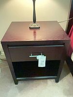 Front view of one nightstand showing drawer, handle and shelf