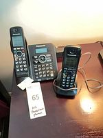 Two Panasonic cordless handsets on desk with charging cradle and answering base