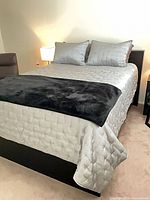 Full view of made queen bed showing headboard, bedding and frame