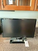 Front view of Samsung TV on stand with remote placed on base