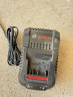 Top view of Bosch BC1880 charger showing logo, red LED indicator, battery slot and attached cord