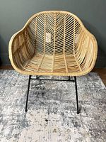 Front view of natural rattan wicker accent chair on black metal legs
