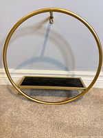 Front view of circular gold metal frame with black shelf