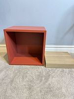 Front view of red EKET cube shelf beside oak veneer LACK shelf