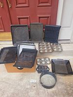 Group of assorted bakeware items laid out including trays, sheets, muffin pans, springform pan