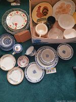 Group of assorted plates, bowls, coasters, glassware displayed on carpet and inside box