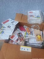 Box containing packaged sticker sheets and assorted iPhone cases