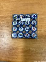 Front view of 16 uncrimped Labatt Blue Calgary Olympic beer caps in clear sleeve