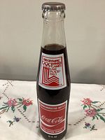 Front of sealed 10 fl oz Coca-Cola commemorative bottle showing Olympic label and contents