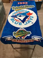 Full view of blue beach towel displaying Toronto Blue Jays logo and World Series Champions graphics