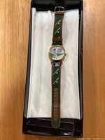 Full view of wristwatch in box showing dial art, strap design and overall condition