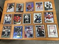 15 assorted sleeved sports cards on table