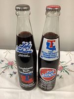 Front view of both championship Coca-Cola bottles showing Lady Techsters labels