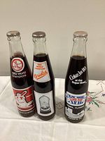 Front view of three unopened commemorative Coca-Cola bottles