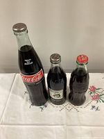 All three sealed Coca-Cola bottles side by side