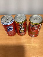 Front view of the three commemorative Coca-Cola cans showing team graphics and championship text