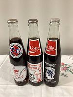 Front view of three commemorative Coca-Cola bottles showing team graphics
