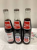 Front view of all three sealed Georgia commemorative Coke bottles