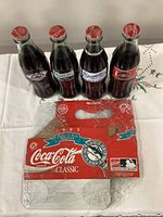 Front view of four sealed commemorative Coca-Cola bottles and flattened Marlins six-pack carrier