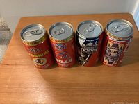 Four NFL Super Bowl commemorative Coca-Cola cans on wooden surface