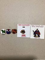 Five NHL team logo lapel pins laid out side by side; two on backing cards
