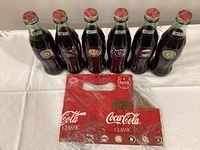 Front view of six unopened Best of the Bay Coca-Cola bottles and wrapped cardboard carrier