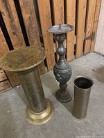 Three metal items: pedestal stand, candlestick, cylindrical vase