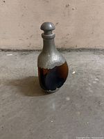 Full front view of decanter showing amber glass body and pewter neck, stopper, base