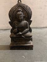 Front view of carved wooden Buddha sculpture showing seated pose and detailing