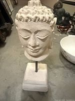 Front view of stone Buddha head on stand