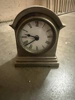 Front view showing clock face, Roman numerals, metal housing