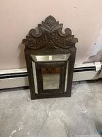 Front view showing carved crest and mirrored door panels