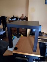 One of the matching square dark-finish end tables placed on a surface to show size and style