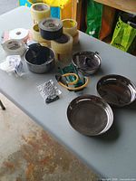 Lot overview: cookware, slingshot, ammo, sunglasses, grater, earplugs, tape rolls