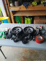 Top-down view showing two large wheels, multiple casters, tape and misc. hardware on table