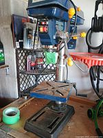Overall view of blue Mastercraft benchtop drill press on workbench
