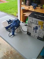 Boxed HomeRight Finish Max sprayer next to unpackaged sprayer on table