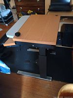 Side view showing laminate top, keyboard tray, metal frame and locking knob