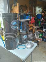 Front view of stacked hydroponic buckets, air pump, tubing and digital meter on table