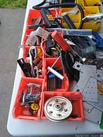 Red plastic bins with assorted hardware, clamp, soldering iron, pliers, pulley wheel visible