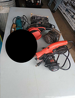All tools on table: angle grinder, charger, red jigsaw, black jigsaw, two sanders