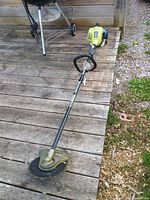 Full view of Ryobi brush cutter on wooden deck