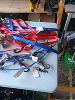 Pile of red/blue tie-down straps and blue/black bungee cords on table