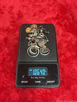 Pile of assorted sterling silver jewelry pieces on scale reading 1.0640 oz