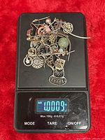 Pile of assorted sterling silver jewelry on scale showing 1.0009 oz